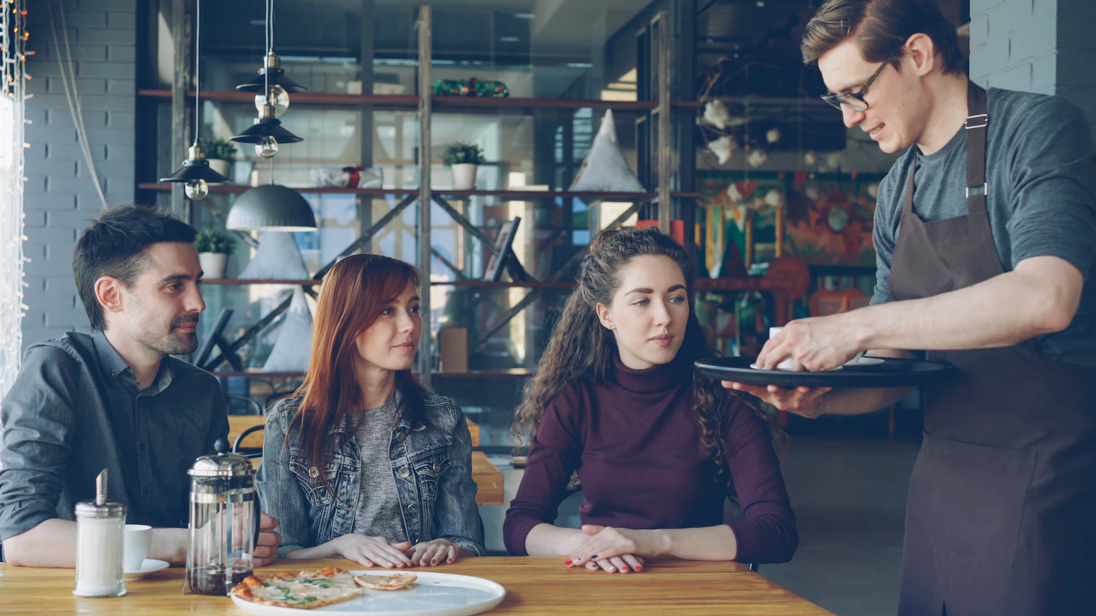 Server speaking with guests at a restaurant table while presenting menu recommendations