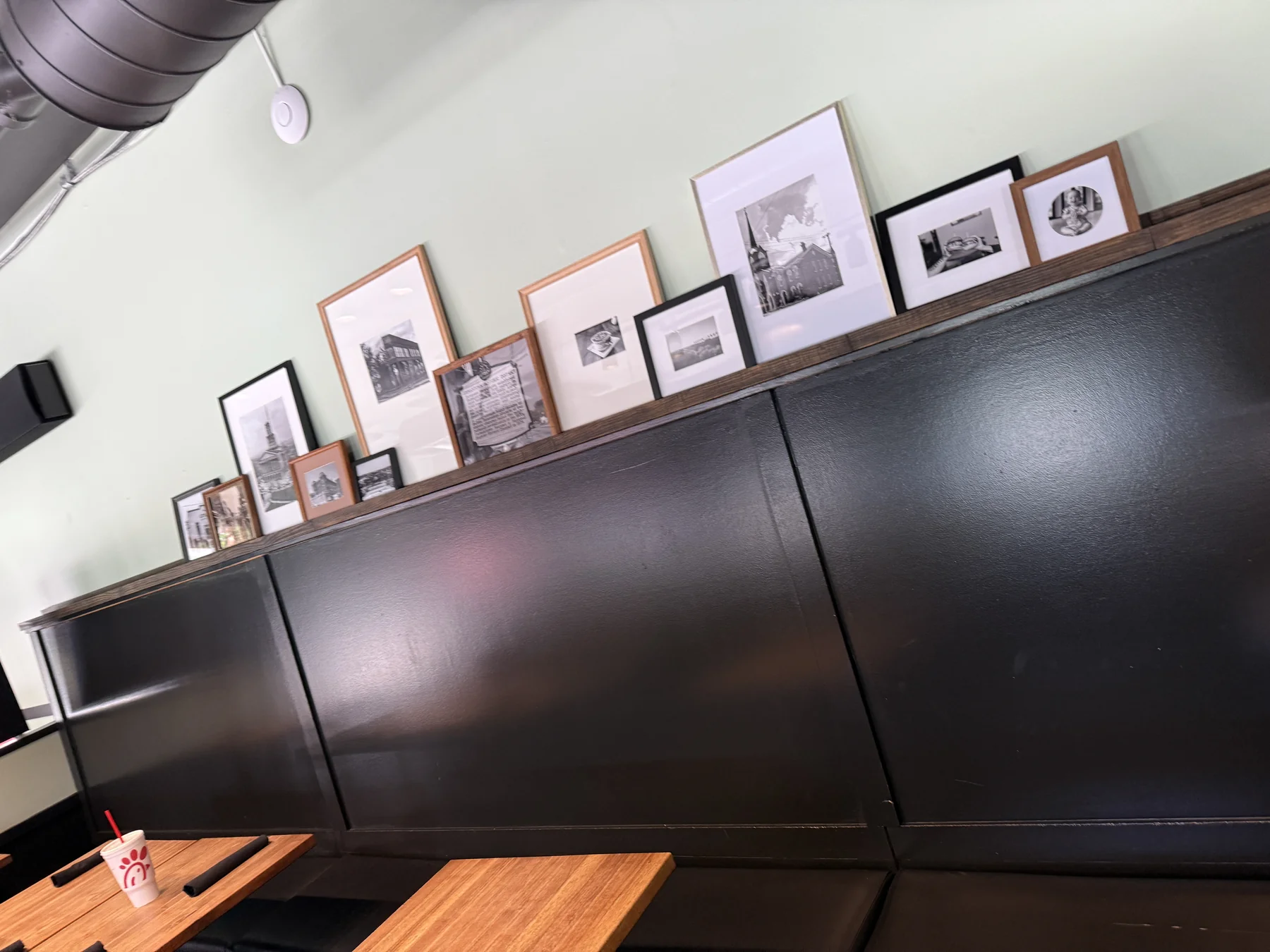 A ledge of framed community photographs and historic images displayed above dark wall paneling