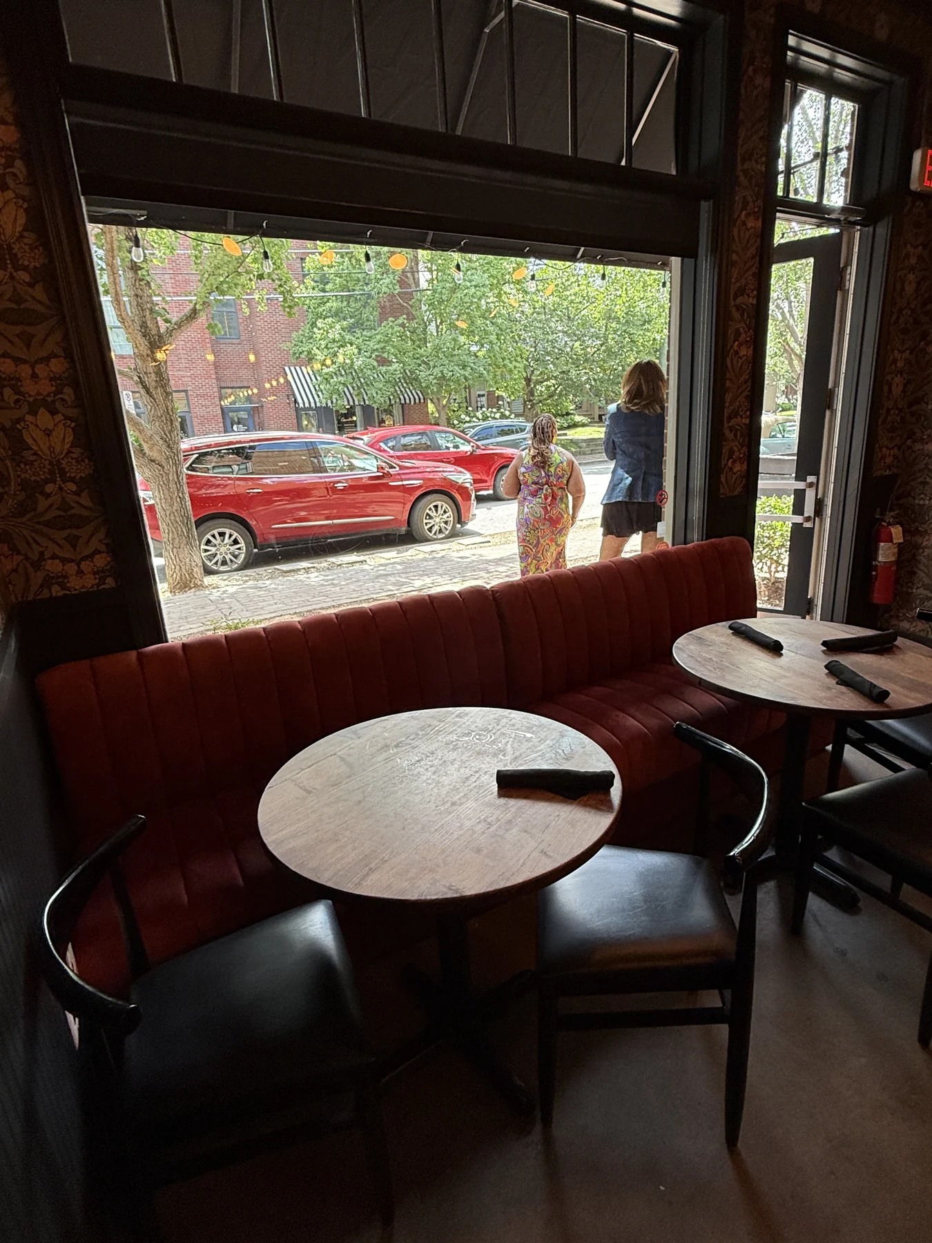 Restaurant booth beside large windows looking out onto a tree-lined neighborhood street
